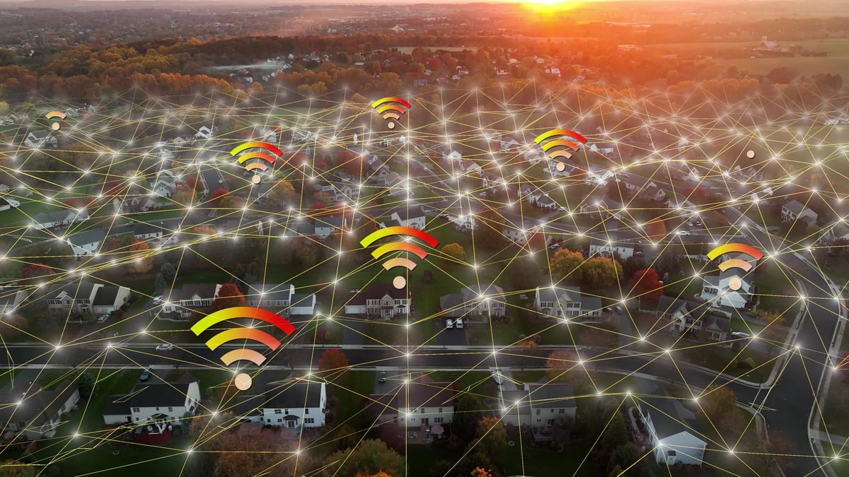A suburban neighborhood overlaid with WiFi and network connection graphics at sunset