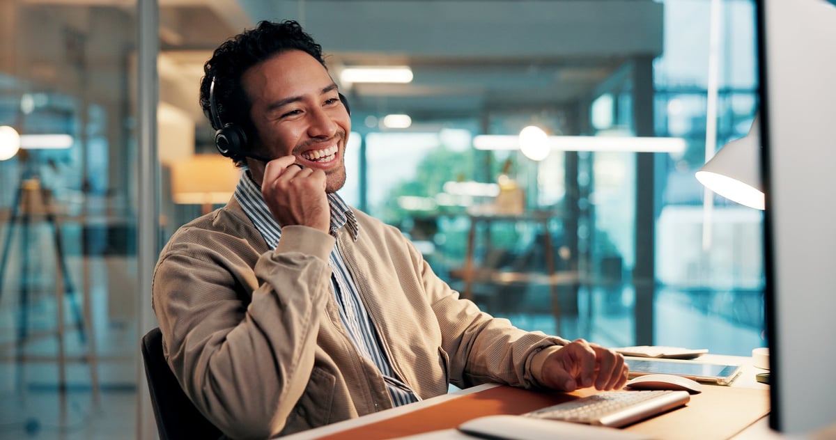 Customer support agent wearing a headset laughing while helping a caller